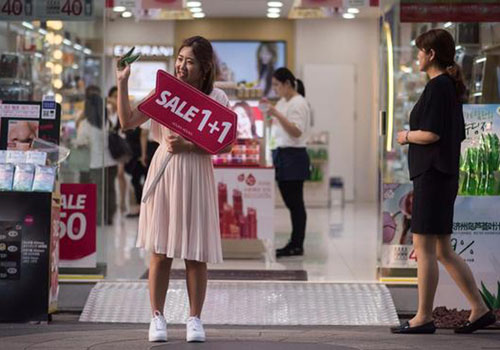 Một cô gái đứng bán hàng trước cửa tiệm mỹ phẩm ở khu Myeongdong, Seoul, Hàn Quốc. Ảnh: AFP